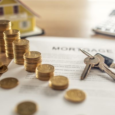 Mortgage contract for the purchase or sale of an apartment house or real estate. Work desk with contract coins model house calculator and pen.