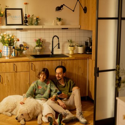 Young couple sit relaxed together with a cute dog on kitchen at home. Home coziness and domestic lifestyle concept